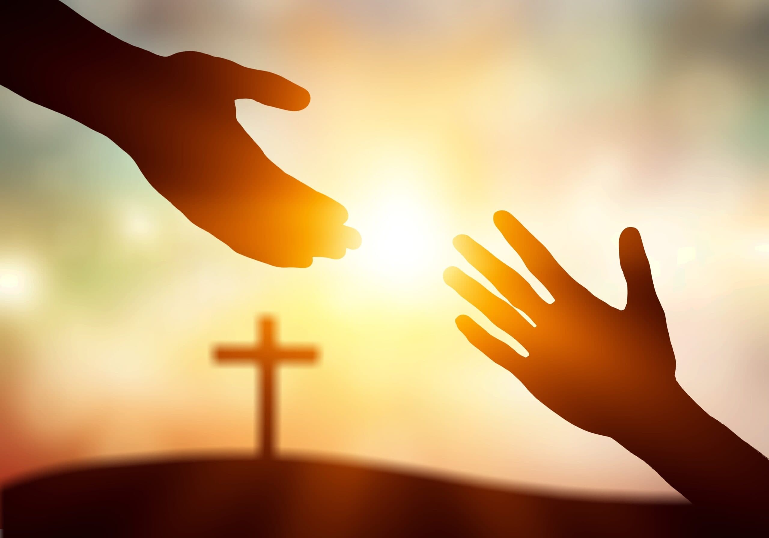 Hands reaching toward each other before a cross