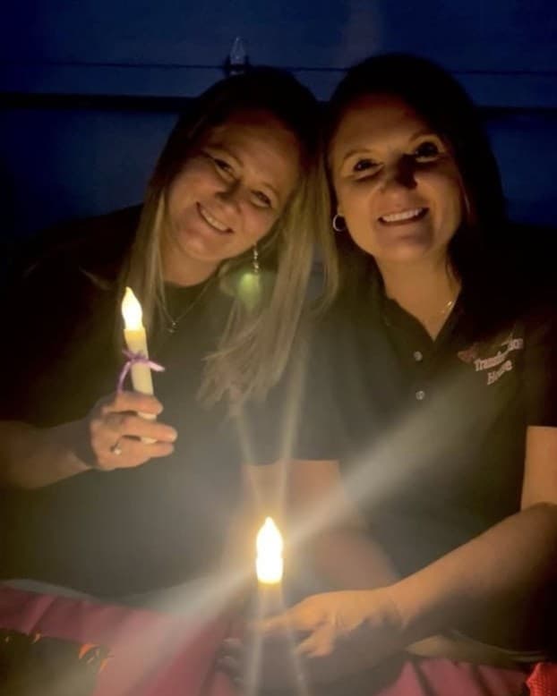 Two smiling women from Butterfly Transformation House holding candles
